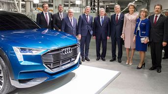 Leurs Majestés le Roi et la Reine de la Belgique à côté d'une voiture conceptuelle Audi e-tron bleue à l'usine Bruxelloise