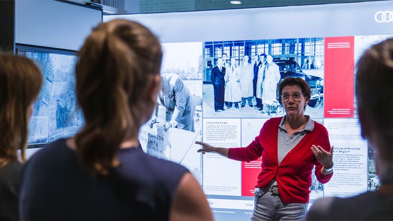 A woman explaining the history of Audi Brussels