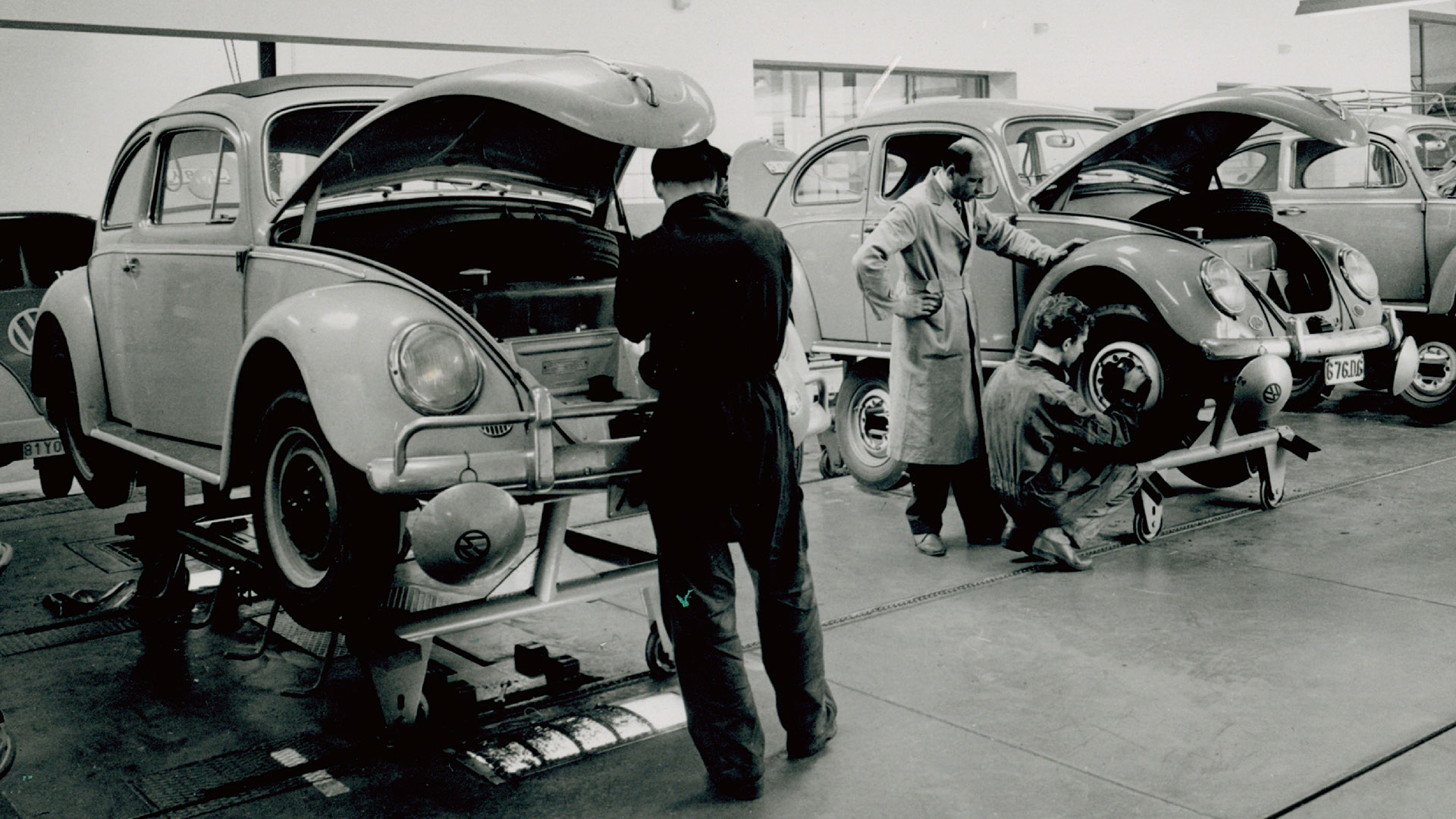 In this black and white photo, you can see 3 workers working on Beetles