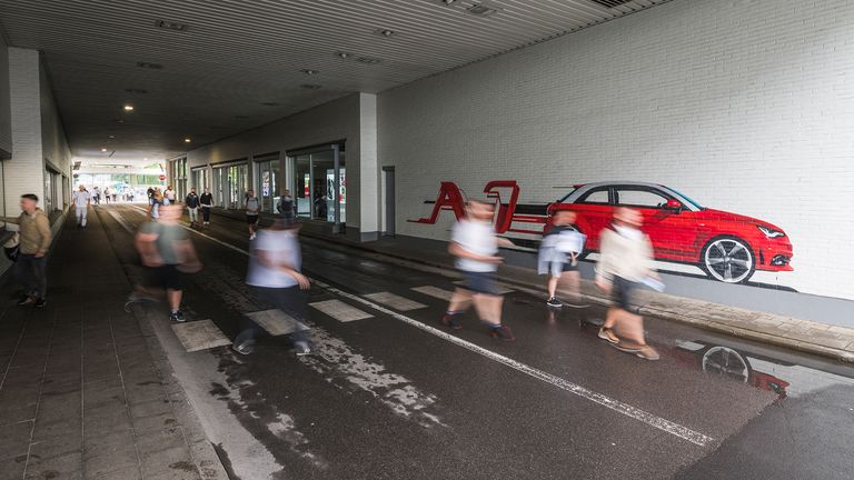 De foto van 6 arbeiders, met de tag van de rode Audi A1 erachter