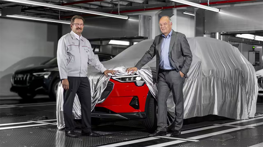 Board members unveil a red Audi e-tron