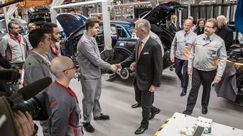 Zijne Majesteit de Koning Filip van België schudt de hand van een arbeider in een productiehal van Audi Brussels